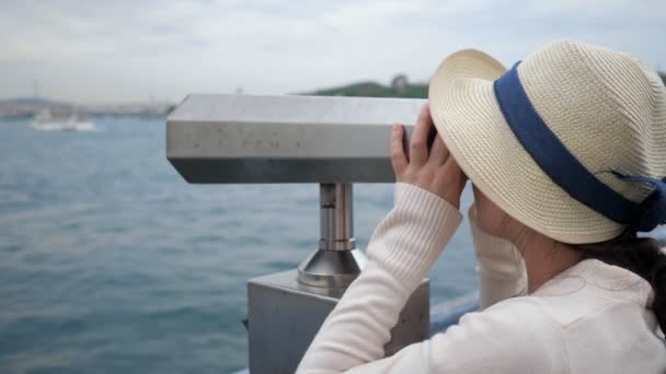 Femme regarde à travers des jumelles explorer la côte sur le remblai — Video