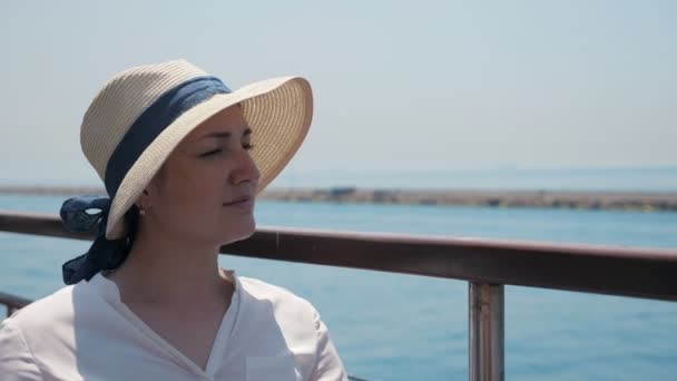 Pretty woman in elegant straw hat sits on ship deck — Stock Video