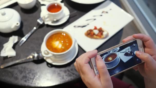 Женщина фотографирует еду по телефону в кафе — стоковое видео