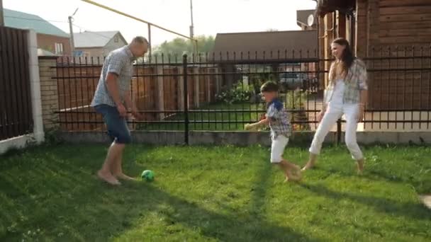 Padres disfrutan de la vida jugando al fútbol con un chico activo en el césped — Vídeos de Stock