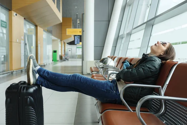 Скучная и уставшая молодая женщина ждет свой рейс в аэропорту сидя в холле . — стоковое фото