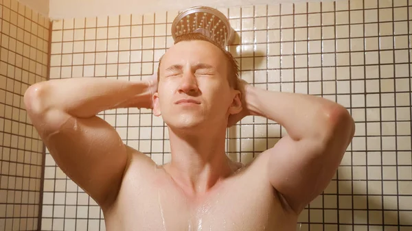 Retrato de un joven tomando una ducha peinándose los pelos con las manos . —  Fotos de Stock