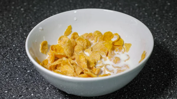 Mezclar los copos de maíz y la leche en un tazón con cuchara y comer para el desayuno . — Foto de Stock