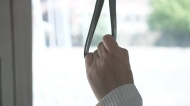 Kadın eli, tramvay alçak açılı çekimde tırabzan bandajı tutuyor