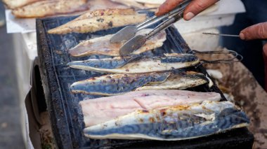 Adam sokak pazarında ızgara beyaz balık balyk kızartma, eller closeup.