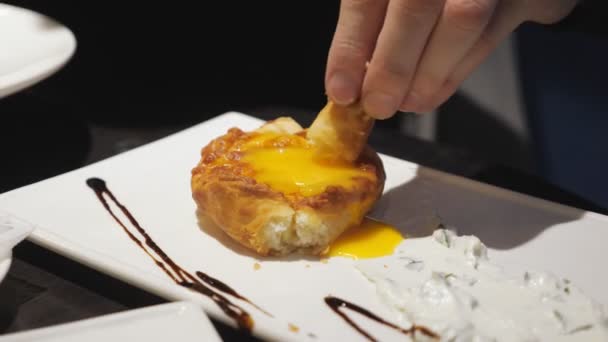 Close-up of juicy khachapuri. The man dips a piece in the yolk — Stock Video