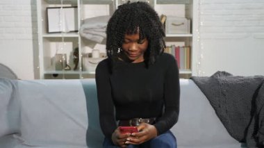 Akıllı telefondaki kıvırcık saçlı Afro-Amerikalı kadın.