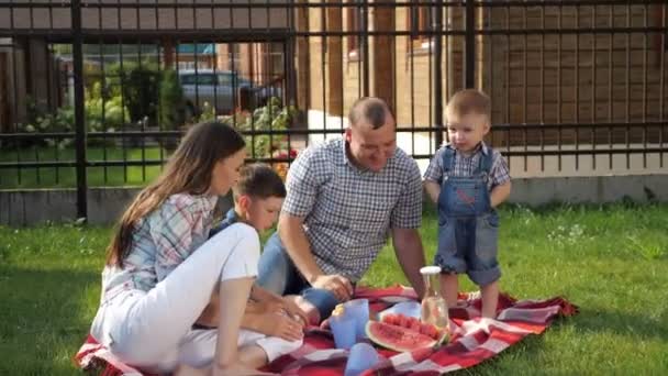 Niños pequeños felices disfrutan de picnic con la madre padre riendo — Vídeos de Stock