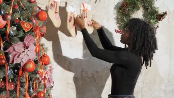 Mosolygós fekete lány díszíti karácsonyfa piros golyók — Stock videók