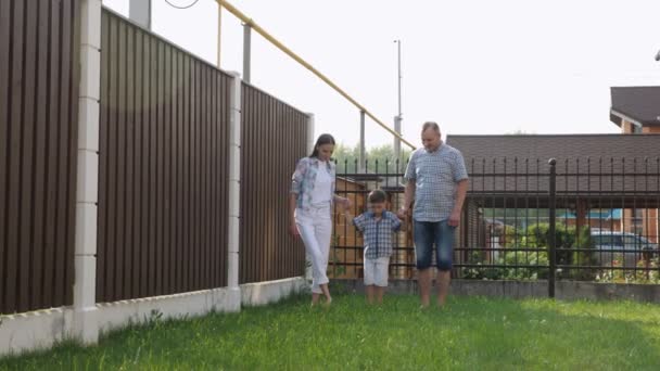 Mały chłopak w białych spodenkach trzyma matkę i ojca ręce — Wideo stockowe