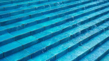 Şehir parkında Çeşme içinde mavi seramik adımlarla su akar.