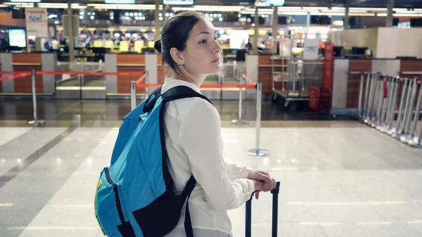 Молодая женщина в аэропорту. Она стоит и смотрит вокруг, вид сзади . — стоковое фото