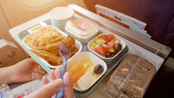 Η γυναίκα τρώει στο αεροπλάνο κατά τη διάρκεια της πτήσης φαγητό σερβίρεται σε ένα δίσκο, χέρι κοντινό. — Φωτογραφία Αρχείου