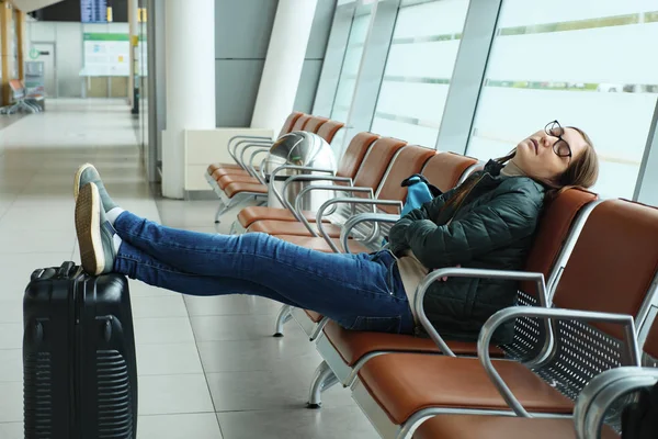 Vervelen jonge vrouw wacht haar vlucht in de luchthaven zittend in Hall. — Stockfoto