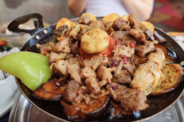 Mulher comendo carne com legumes servidos em frigideira no restaurante, close-up . — Fotografia de Stock