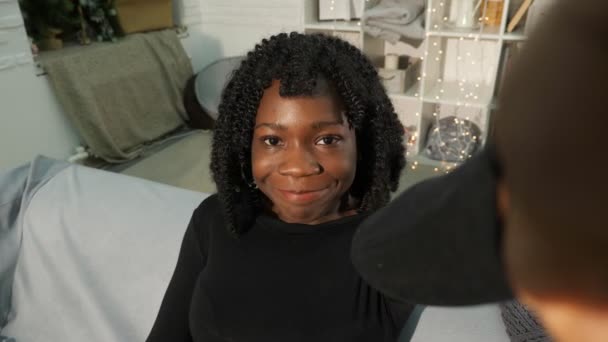 Привлекательная молодая черная женщина с вьющимися волосами выглядит улыбающейся — стоковое видео
