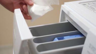 Kadınlar modern çamaşır makinesine çamaşır tozu döker.