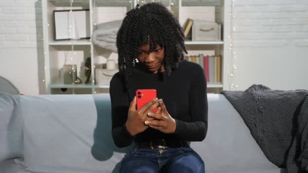 African American lady with curly hair types on smartphone — Stock Video