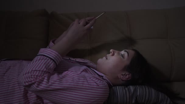 Fiatal nő átlapozza a közösségi média takarmány a telefonján, és elalszik — Stock videók
