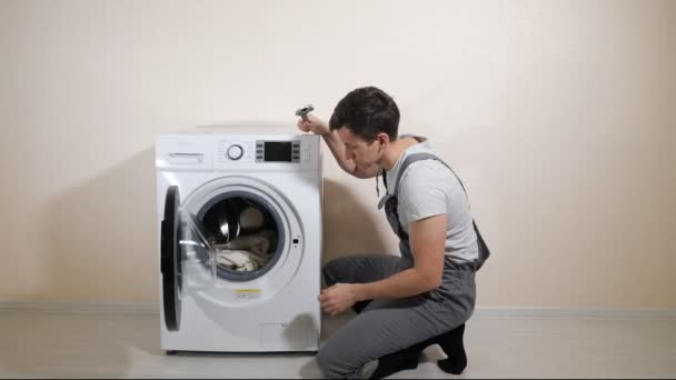 Reparos serviceman máquina de lavar roupa quebrada perto da parede bege — Vídeo de Stock