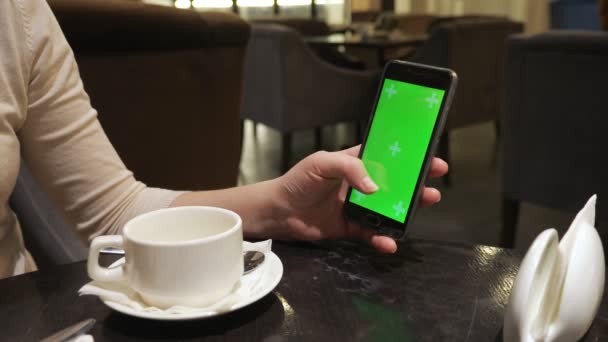 Meninas mão folheando através de um telefone sensor com uma tela verde no café — Vídeo de Stock
