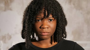 Siyah elbiseli ciddi bir zenci kadın başını sallıyor ve bakıyor.