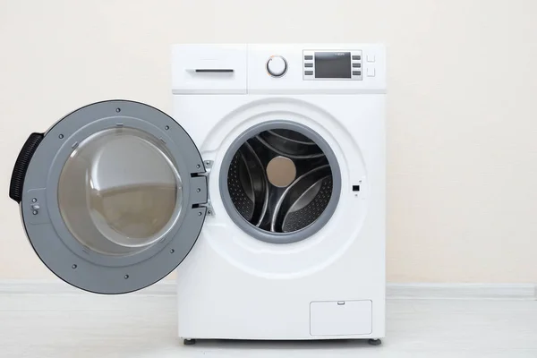 Waschmaschine mit offener Tür am Boden gegen beige Wand — Stockfoto