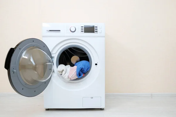 Waschmaschine mit Wäsche in Trommel nahe beiger Wand — Stockfoto