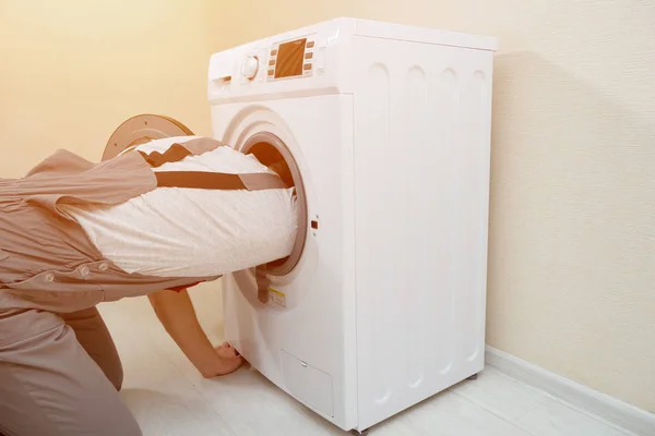 Mitarbeiter repariert kaputte Waschmaschine an beiger Wand — Stockfoto