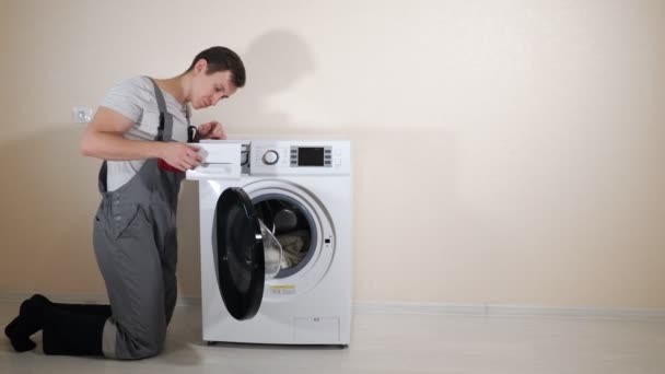 Young serviceman in grey uniform repairs broken washing machine — 비디오