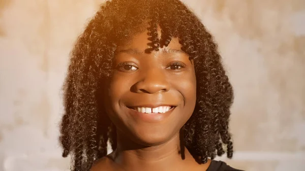 Afroamerykanka z kręconymi włosami patrzy przed siebie i uśmiecha się — Zdjęcie stockowe
