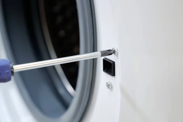 Mann dreht Schraube an Waschmaschinentür — Stockfoto