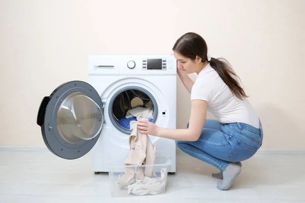 Kvinna laddar smutsiga kläder i bricka nära beige vägg — Stockfoto