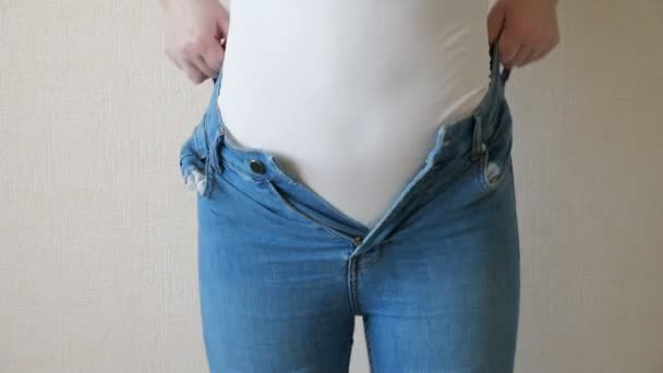 Jonge vrouw worstelt naar knop haar jeans — Stockvideo