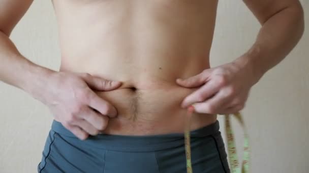 Giovane uomo palpa lo stomaco e i lati ed effettua misurazioni con un nastro di centimetri — Video Stock