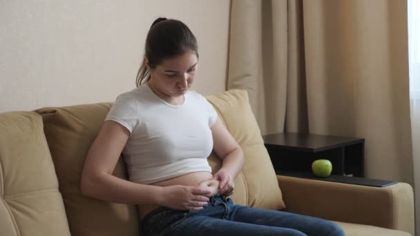 Mujer regordeta está comiendo una manzana mientras está sentado en el sofá . — Vídeos de Stock