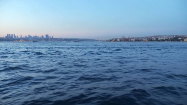 Derin mavi deniz dalgaları alacakaranlıkta gemiden şehre vuruyor.