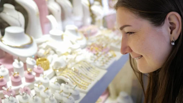 Chica mira joyas caras y hace la elección en la tienda — Foto de Stock