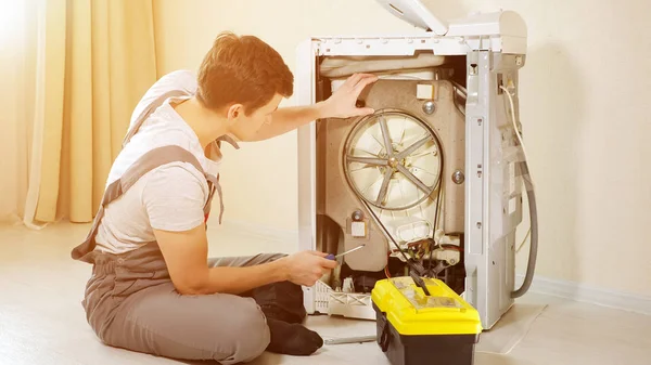 Master opent achterpaneel van kapotte wasmachine — Stockfoto