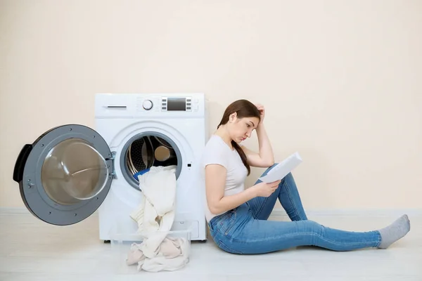 Hausfrau lernt Einstellungen der neuen Waschmaschine auf dem Fußboden — Stockfoto