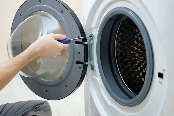 Man twisting screw on washing machine door closeup — Stock Photo, Image