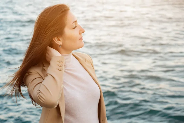 Žena se dotýká vlasy těší krásné přírodě proti moři — Stock fotografie