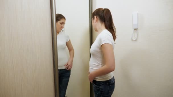 Junge übergewichtige Frau tastet vor Spiegel ihre Seiten und ihren Bauch ab — Stockvideo