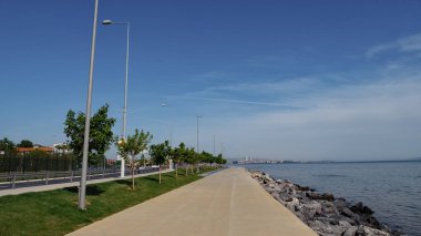 Deniz manzarası ve şehir manzarasıyla rıhtımda yürüyorum.