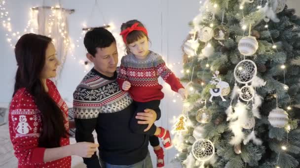 Ouders met dochter versieren verlichte kerstboom — Stockvideo