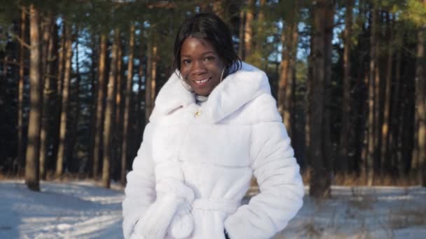 Negro chica poses cogidas de la mano en bolsillos contra snowy park — Vídeo de stock