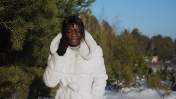 Fille avec la peau noire marche le long de la forêt et parle au téléphone — Video