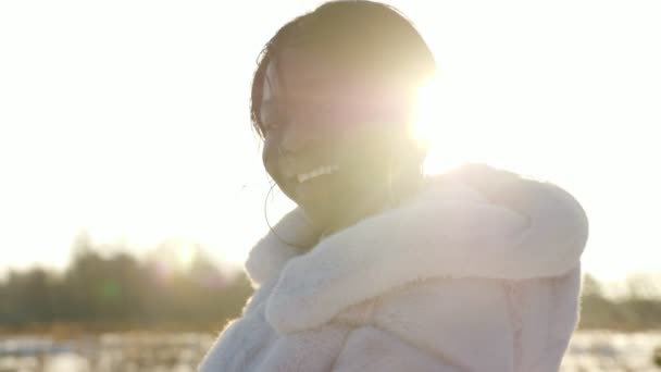 Sonriente chica de piel oscura posa contra el campo cubierto de nieve vacío — Vídeo de stock