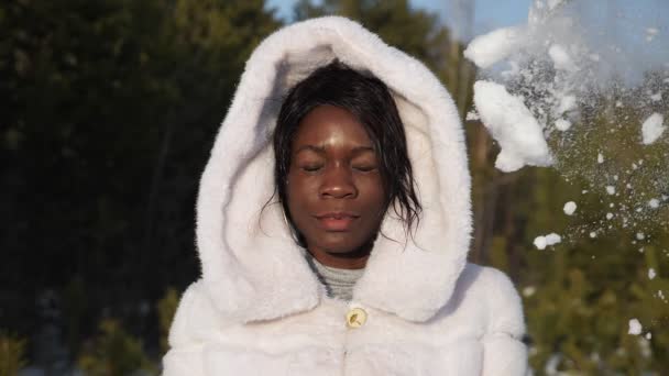 Boldog fekete lány prémkapucnis kap hógolyó az arcába mosolygós — Stock videók
