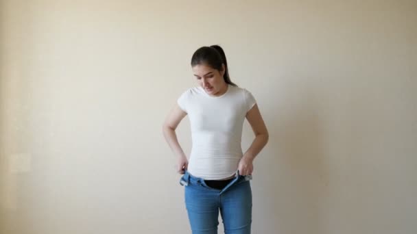 Brunette struggles to pull on her jeans and cant button them — Stock Video